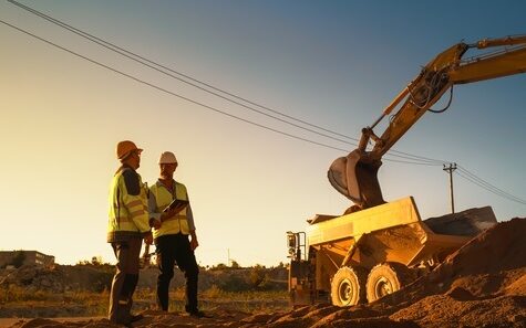 np_Real Estate Investor With Tablet And Project Manager Talking On Construction Site Of Apartment Building. Colleagues Wearing Hard Hats And Watching Heavy Machinery Working. Sunny Day_56G6MY_free